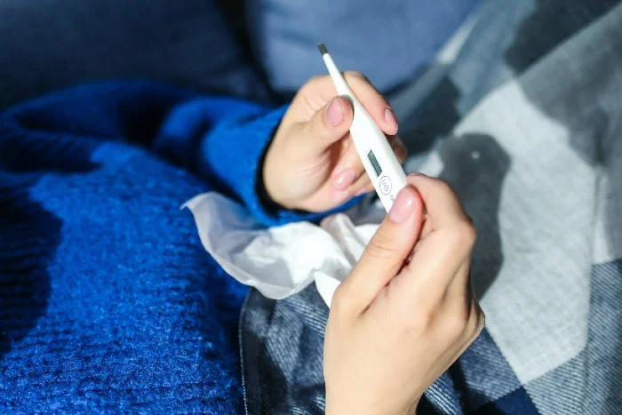 Ruce drží teploměr a vreckovku při příznacích RS viru