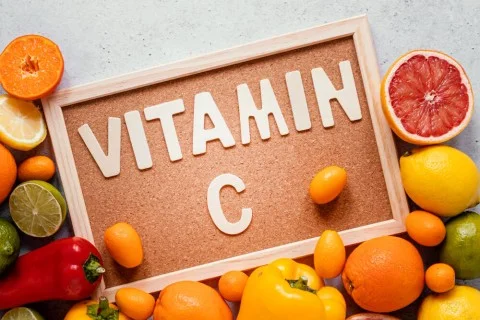 Tabule s nápisem vitamín C obklopená ovocem bohatým na tento vitamin.