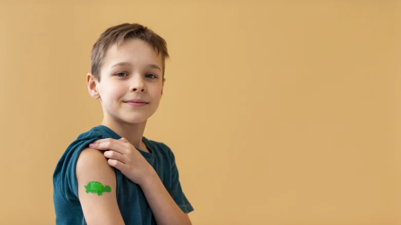 Chlapec s očkovacím nálepkou na paži před žlutým pozadím.
