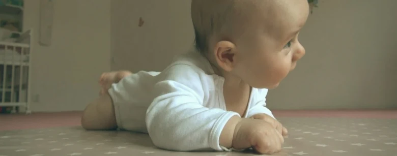 Miminka leží na břiše a podívala se do stran.