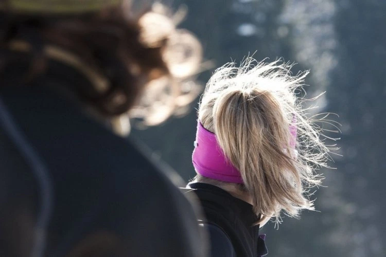 Žena s blond vlasy v copu a růžovou páskou za uchem