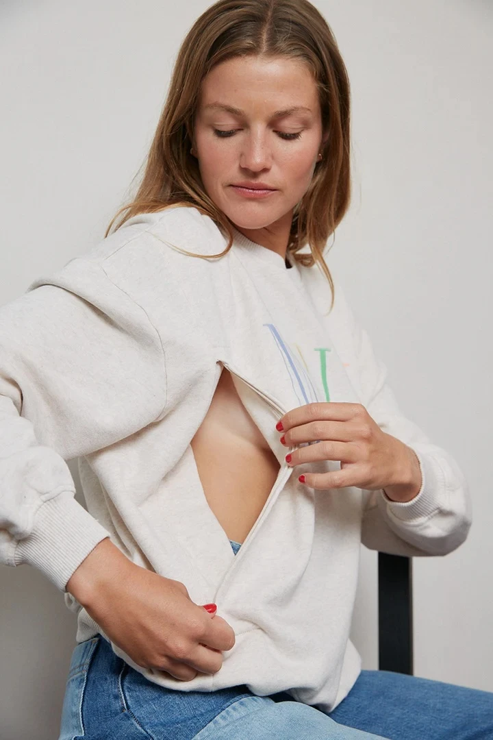 Žena otevírá zip na svetrku pro kojení