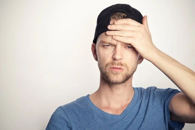 Muž drží ruku na čele jako příznak mrtvice.
