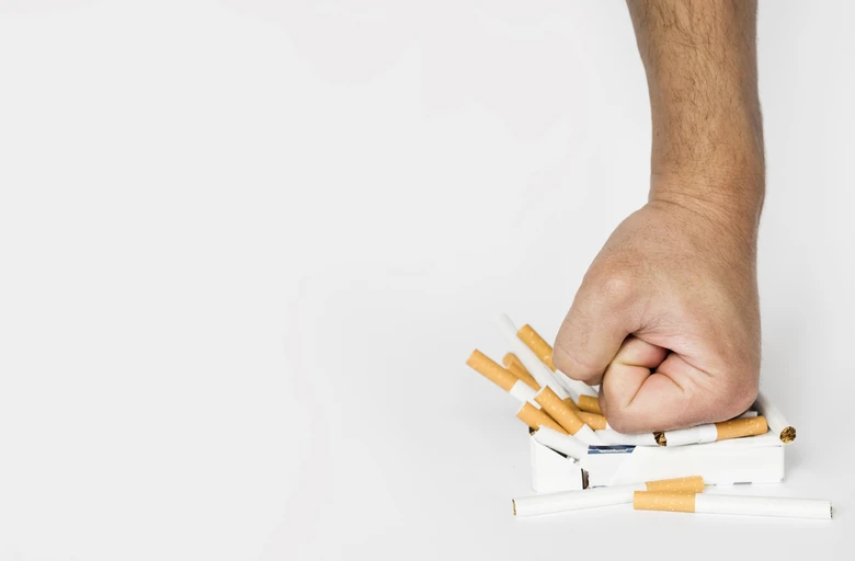Ruka ničí krabičku cigaret jako metafora pro přestání s kouřením.