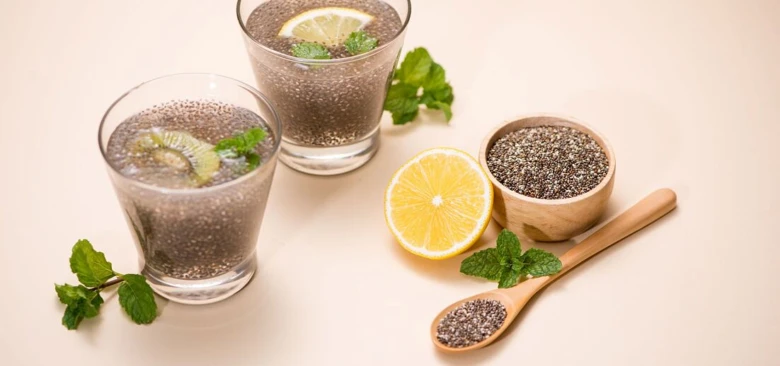 Sklenice s chia pudinkem, miska se semínky a citron.