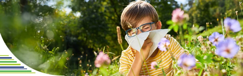 Chlapec s alergií na pyl v zahradě se třese z kýchání.