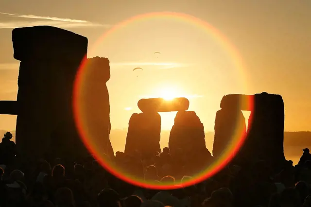 Stones of Stonehenge při západu slunce s davem diváků.