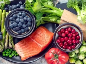 Salmon, bobulky, zelenina na talíři jako protizánětlivé potraviny.