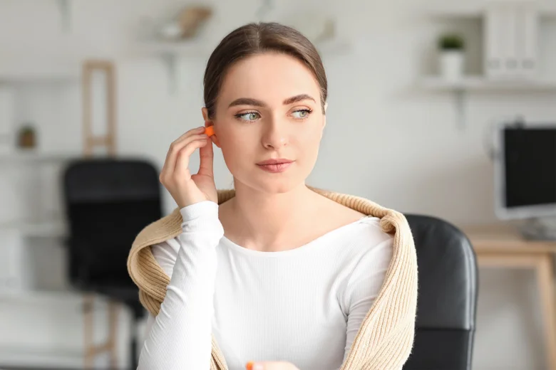 Žena vkládá do ucha oranžovou vložku proti hluku.