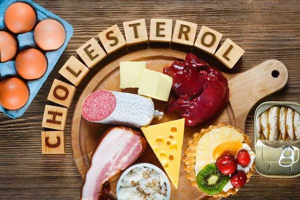 Různé potraviny s vysokým cholesterolem na dřevěném talíři.