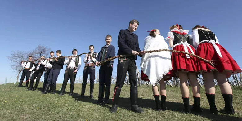Lidé v lidových kostýmech drží věnovanou větvičku na Velikonoce.