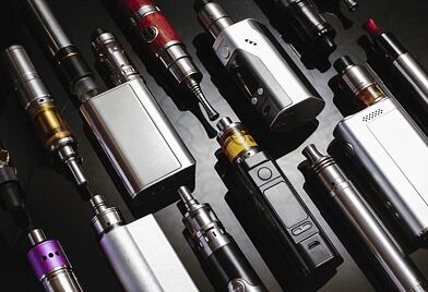 Různé elektronické cigarety a vapery na tmavém pozadí.