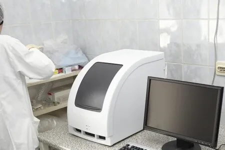 Bílý lékařský přístroj v laboratoři s počítačem.