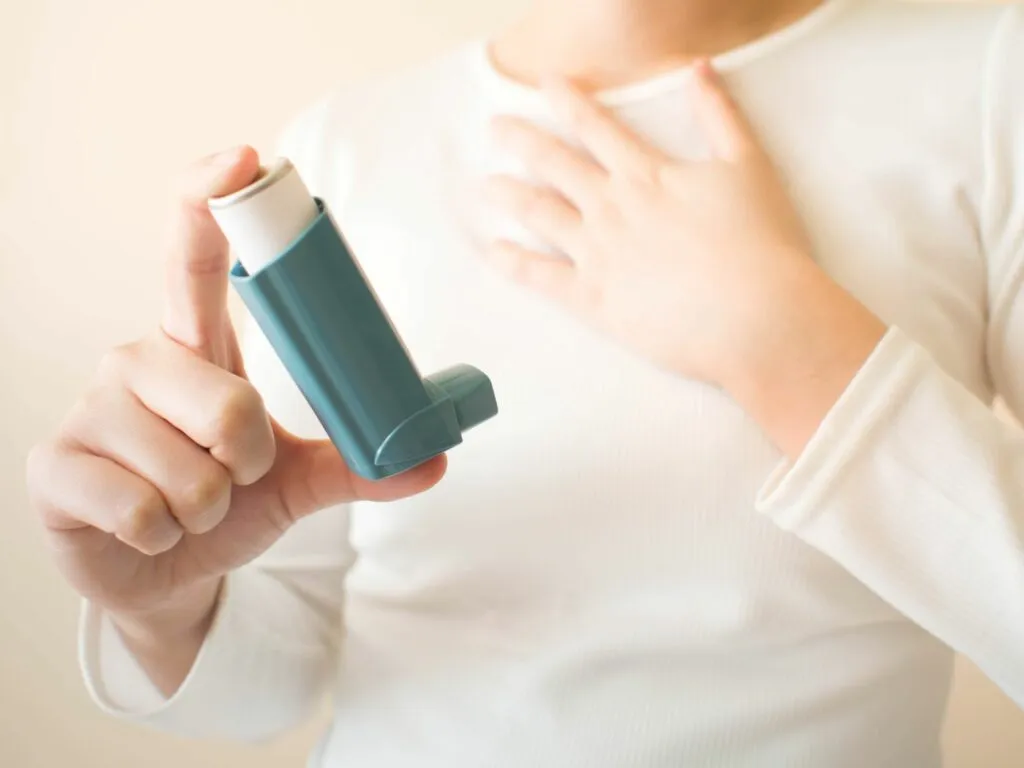 Člověk drží inhalátor při alergie na kočky.