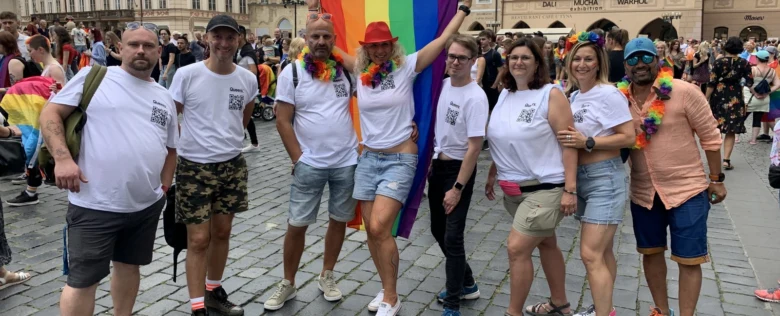Skupina lidí na hrdé akci s duhovými doplňky.