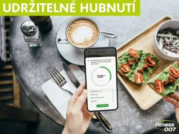 Ruka drží telefon s aplikací pro sledování kalorií při snídani.