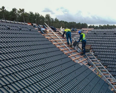 Stavebníci montují střechu s taškami na dřevěných latích