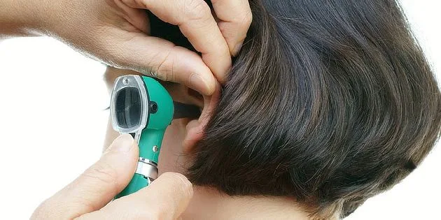 Lékař zkoumá ucho pomocí otoskopu při vyšetření sluchu.