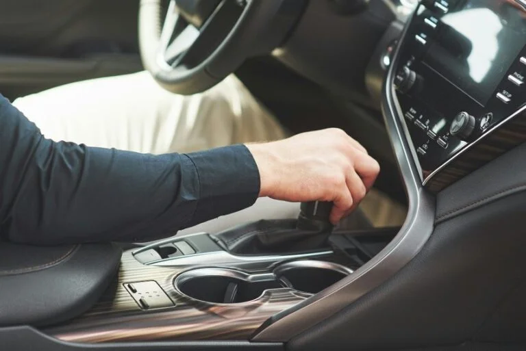 Ruka řidiče mění převod v automobilu s automatickým převodem.