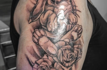 Detailní tetování králíka s růžemi na rameni ukazuje výslednou práci po zahojení.