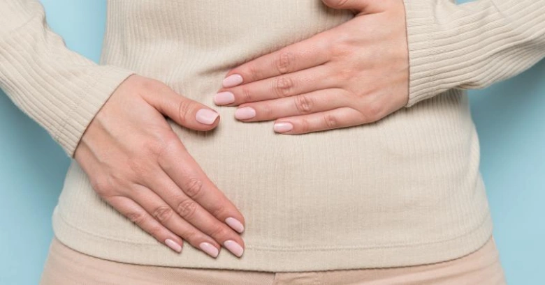 Žena drží ruce na břiše jako přírodní metoda pro menstruaci.