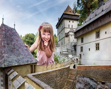 Dívka v růžovém stojí na hradě s úsměvem.