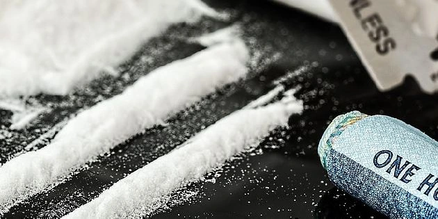 Bílá prášek v řadách s nůžkami na holení a složenou stříbrnou mincí.