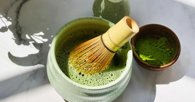 Příprava zeleného čaje Matcha v misce s bambusovým šlehačem.