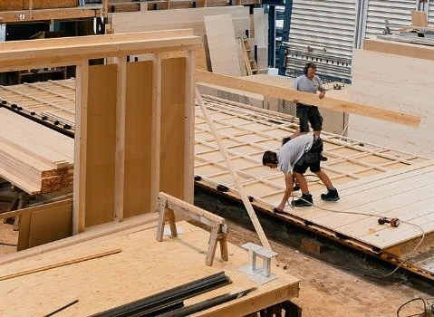 Muži staví dřevěný dům na klíč v dílně.