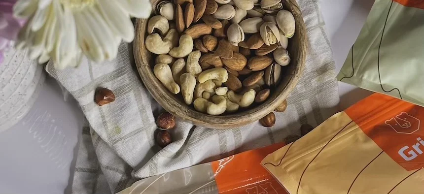 Míchané ořechy v dřevěné mísce na ubrusu.