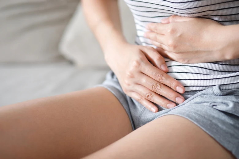 Žena drží břicho po porodu - první menstruace