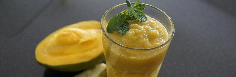 Sklenička s hruškovým šlehaním vedle poloviny zralého mangga