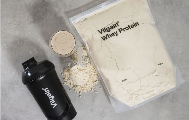 Sáček bílkovin Whey Protein s lžičkou a mixérem.