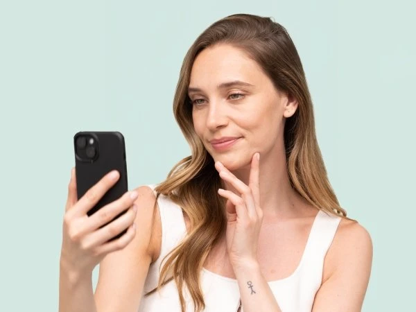 Žena se dívá na telefon s myšlenkou o péči o pleť.