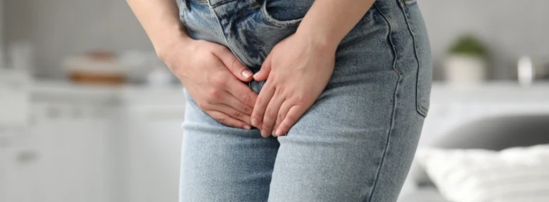 Žena drží spodní břicho kvůli bolesti při zánětu močového měchýře.