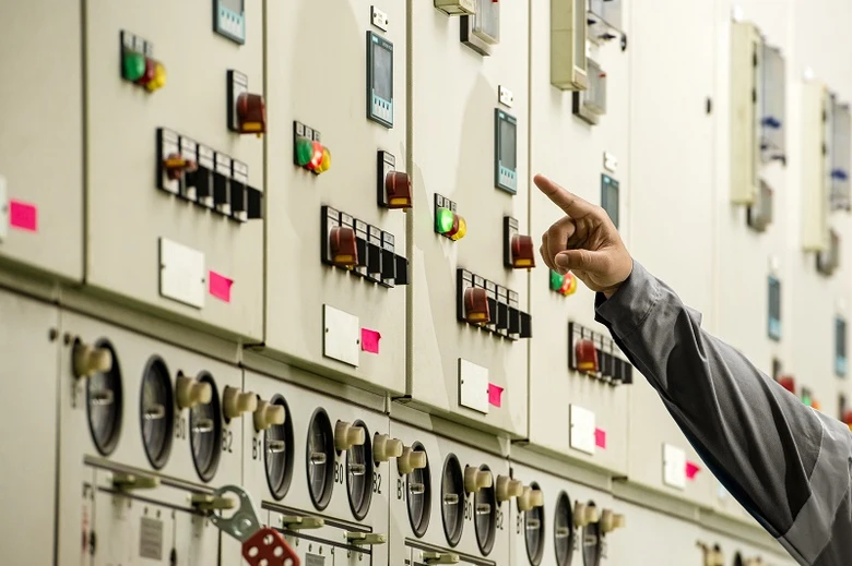 Elektrikář ukazuje na spínače v domovním rozvaděči.