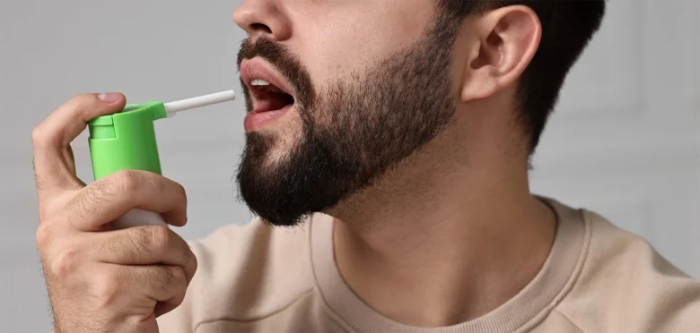 Muž používá inhalátor pro úlevu od bolesti v krku.