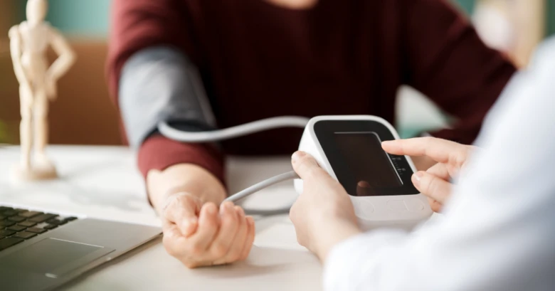 Lékař měří krevní tlak pacienta pomocí elektronického přístroje.