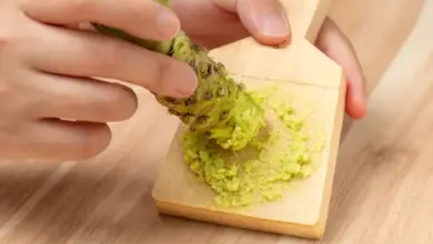 Rozdírání čerstvého kořene wasabi na dřevěné desce.