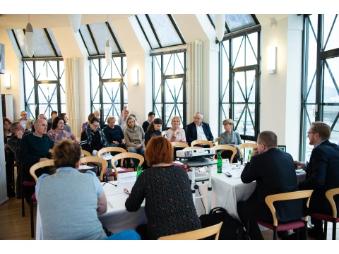 Skupina lidí sedí v konferenčním sále během diskuse.