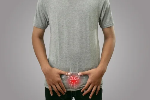 Muž drží břicho s ikonou prostaty na tričku.