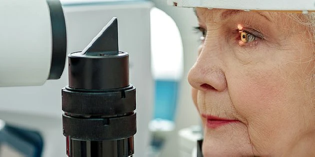 Žena se podívá do oftalmologického přístroje při vyšetření zraku.