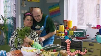 Muž a žena drží svazky čerstvé řeřichy v kuchyni.