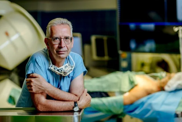 Lékař v nemocničním prostředí s pacientem na lůžku.