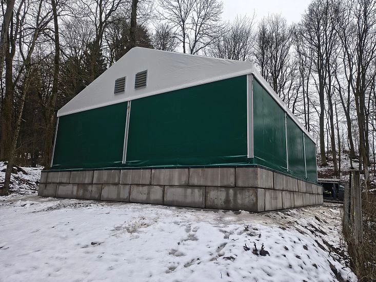 Zelená stanová budova na sněhu v lesu