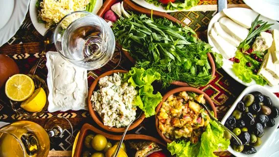Stůl s mediterránskou stravou: zelenina, olive, sýr a víno.