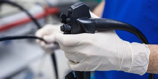 Endoskop držící lékař v rukavicích pro vyšetření tlustého střeva