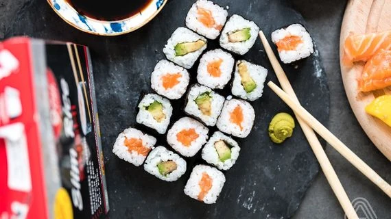 Sushi rolly s lososem a avokádem na tmavém podkladu.