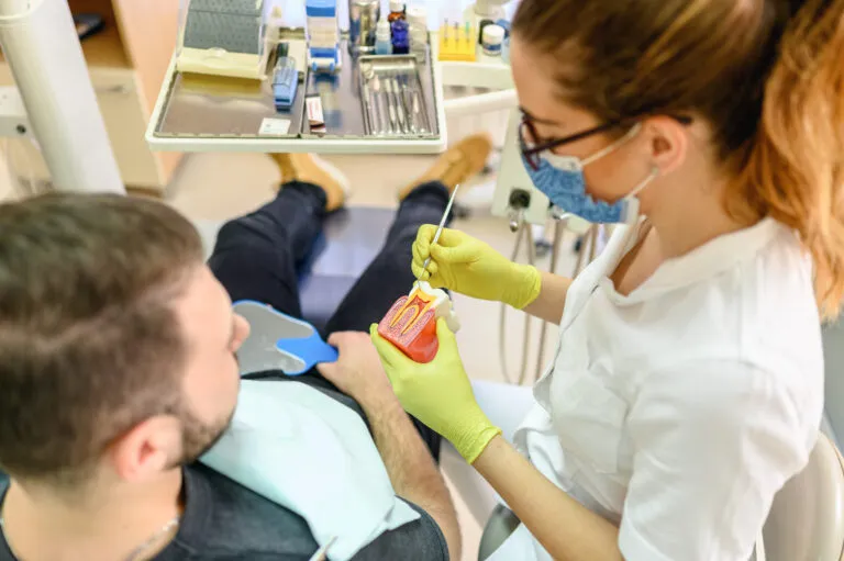 Zubní lékař léčí zánět dásní pacienta pomocí nástrojů.