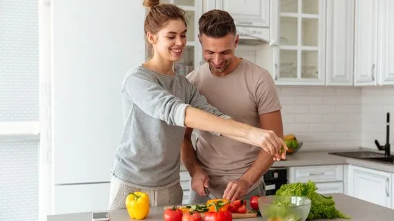 Muž a žena připravují čerstvé zeleninu v kuchyni pro zdravý jídelníček.